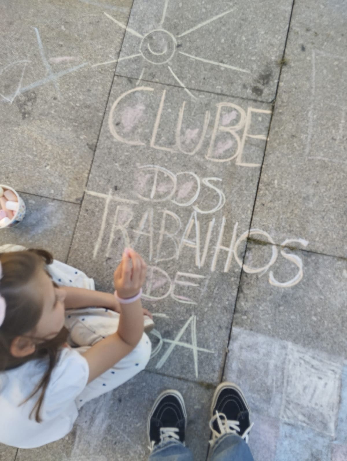 Criança a escrever o nome do clube a giz no pátio